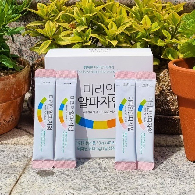 미리안 알파자임 상자와 분홍 스틱, 초록 잎 앞
